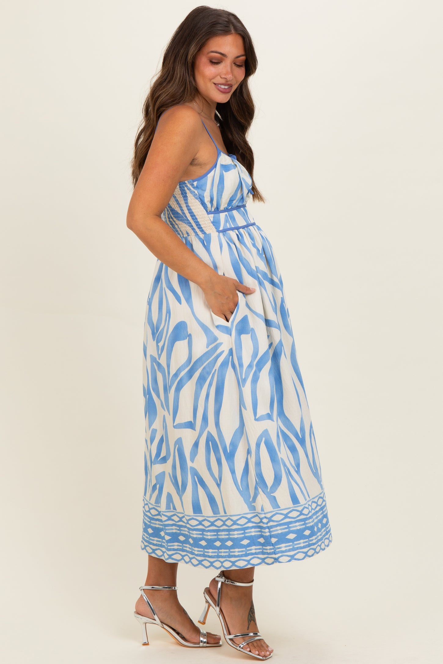 woman wearing a blue and white patterned maternity dress with pockets and a flowing skirt, showing her baby bump