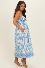 woman wearing a blue and white patterned maternity dress with pockets and a flowing skirt, showing her baby bump