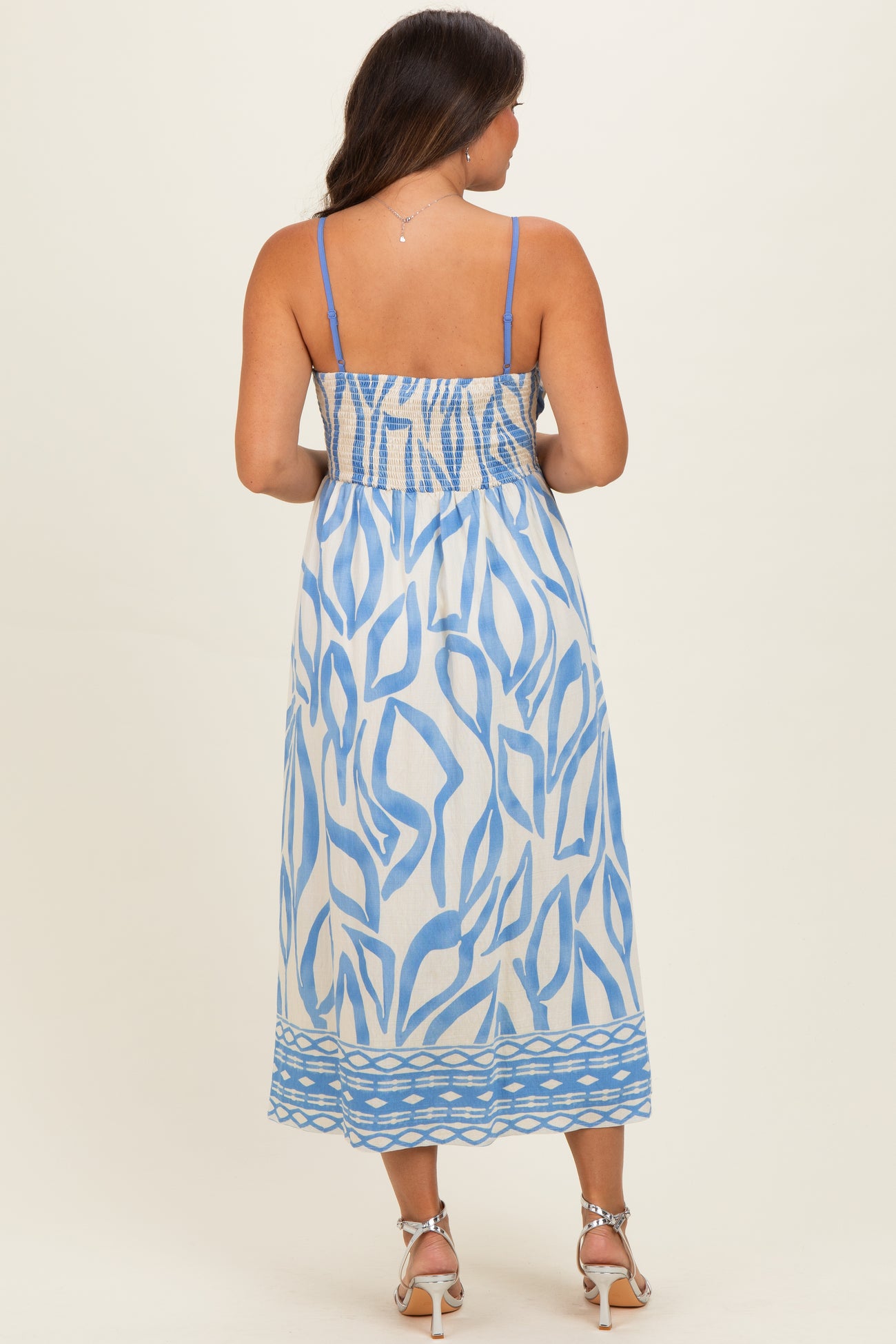 woman wearing a blue and white patterned maternity maxi dress with smocked bodice and spaghetti straps, showing her baby bump