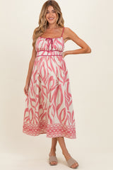 woman wearing a pink and white patterned maternity dress with spaghetti straps and a cinched waist, baby bump visible