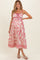 woman wearing a pink and white patterned maternity dress with spaghetti straps and a cinched waist, baby bump visible
