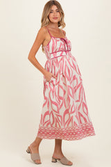 woman wearing a pink and white patterned maternity dress with a fitted bodice and pockets, showing her baby bump