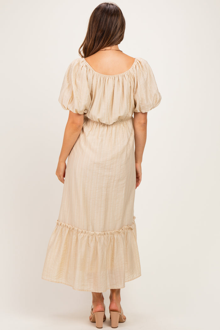woman wearing a light beige maternity dress with puff sleeves and a ruffled hem, showing a subtle back view