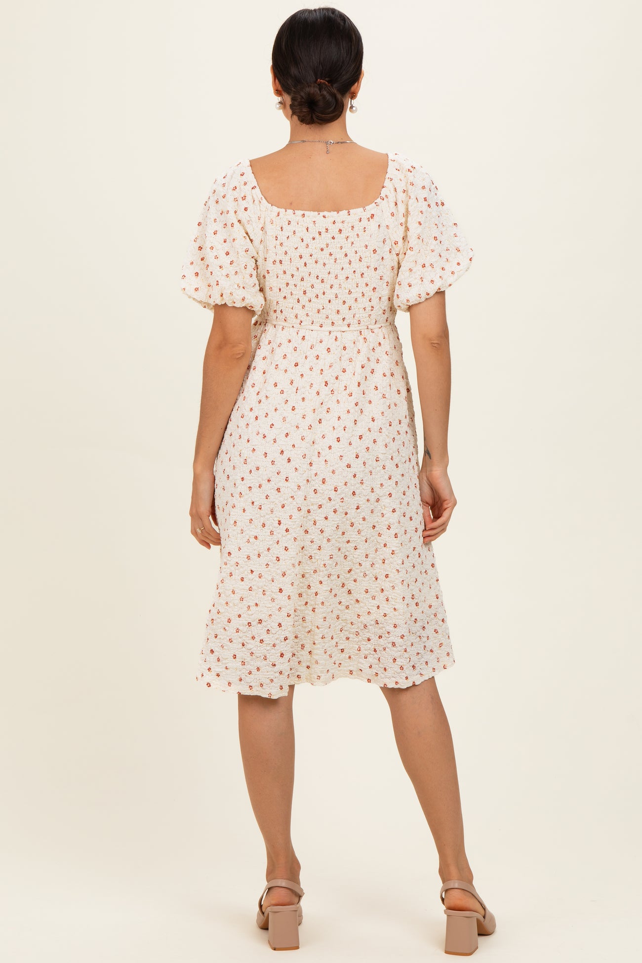 woman wearing a white floral midi dress with puff sleeves and a square neckline, shown from the back