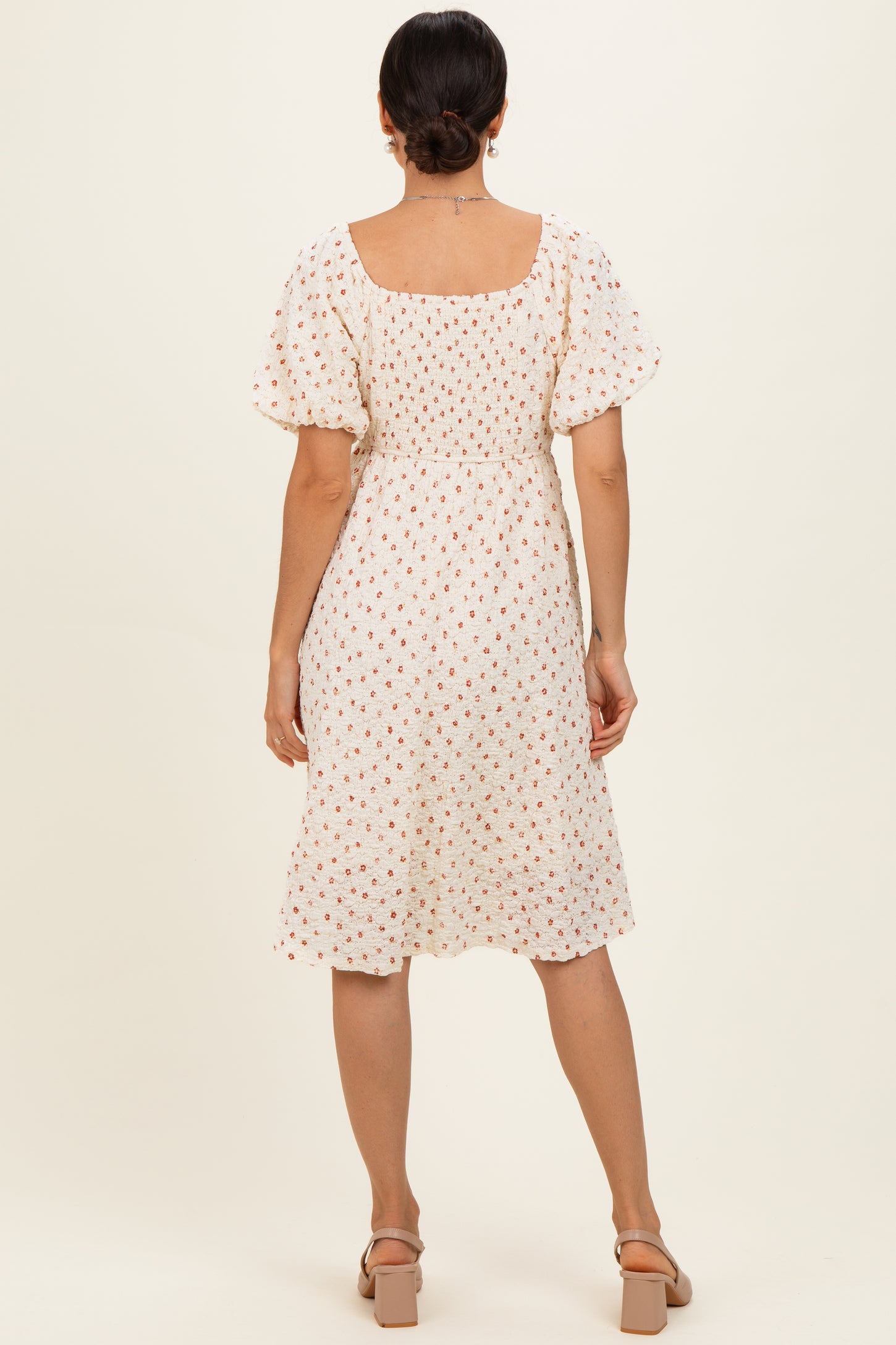 woman wearing a white floral midi dress with puff sleeves and a square neckline, shown from the back
