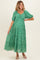 woman wearing a green floral maternity maxi dress with puff sleeves and a cinched Empire waist showcasing her baby bump