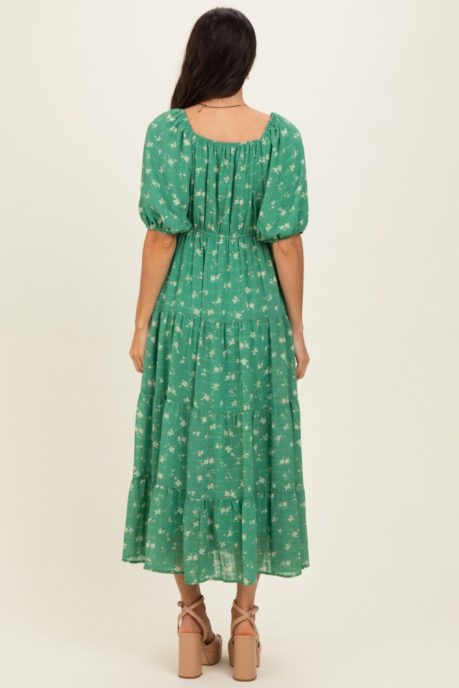 woman wearing a green floral maxi dress with puff sleeves and a tiered skirt, view from the back