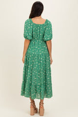 woman wearing a green floral maxi dress with puff sleeves and a tiered skirt, view from the back