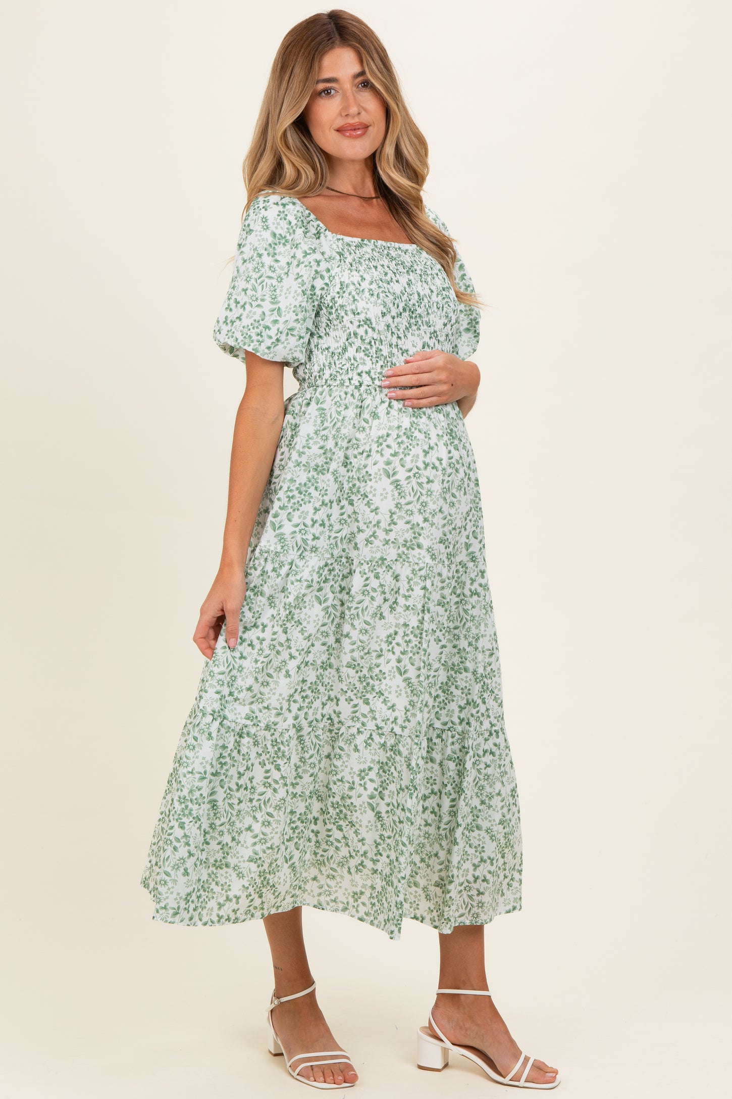 woman wearing a green floral maternity dress with puff sleeves and a baby bump visible