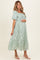 woman wearing a green floral maternity dress with puff sleeves and a baby bump visible