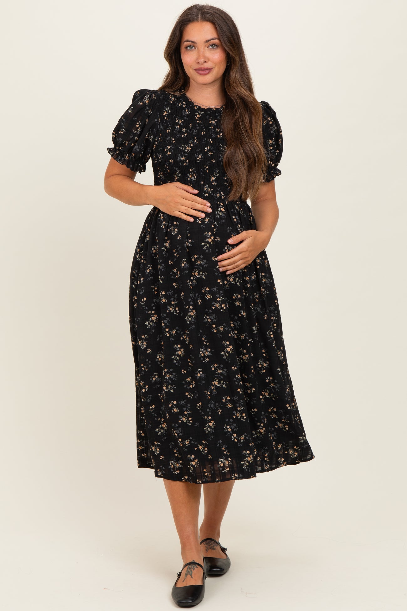 woman wearing a black floral maternity dress with puff sleeves and a baby bump visible