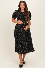 woman wearing a black floral maternity dress with puff sleeves and a baby bump visible