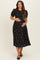 woman wearing a black floral maternity dress with puff sleeves and a baby bump visible