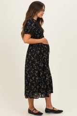 woman wearing a black floral maternity dress with puff sleeves and a visible baby bump