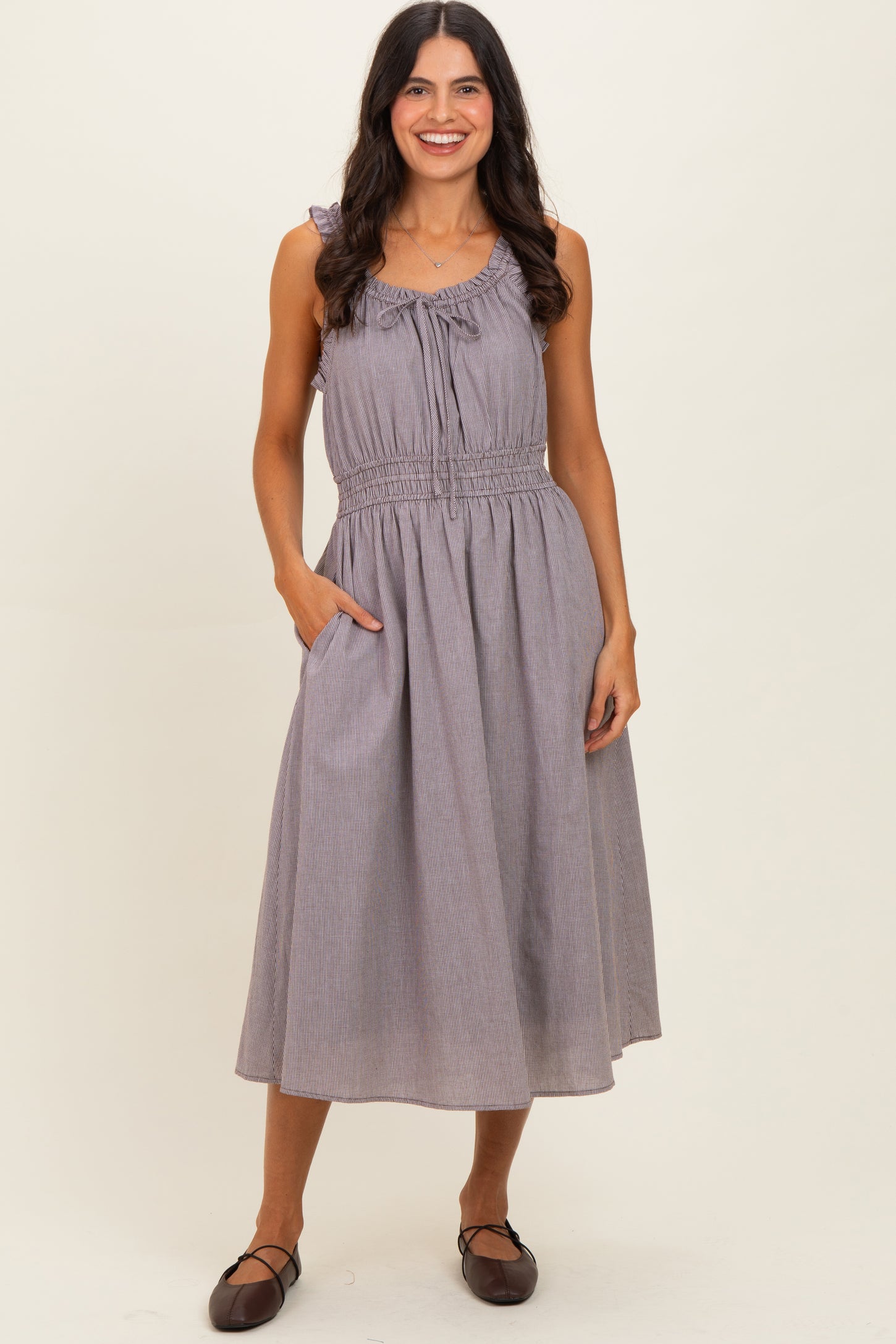 woman wearing a gray and white striped midi dress with ruffle details and pockets