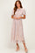 woman wearing a light pink floral midi dress with puff sleeves and a smocked bodice, standing in stylish heels
