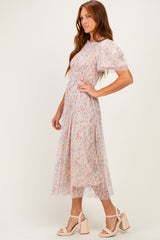 woman wearing a floral print midi dress with short puff sleeves and a cinched waist, standing in profile