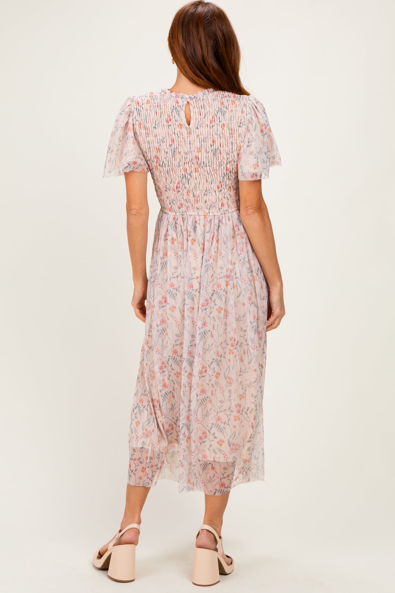 woman wearing a pastel floral midi dress with puff sleeves and a smocked back, showing a keyhole detail at the neck