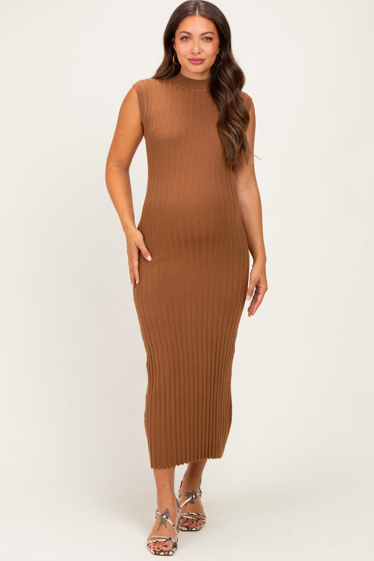 woman wearing a ribbed brown maternity dress with a sleeveless design and a fitted silhouette, showing her baby bump