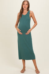 woman wearing a teal maternity maxi dress and holding her baby bump