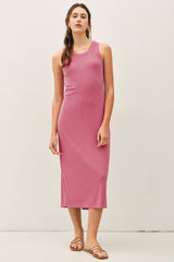 woman wearing a pink sleeveless ribbed maxi dress with a fitted silhouette and standing against a neutral background
