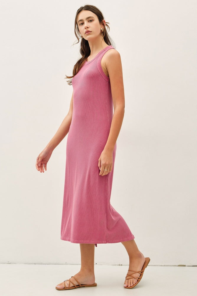 woman wearing a sleeveless pink midi dress with a fitted silhouette and side slits, walking on a white background
