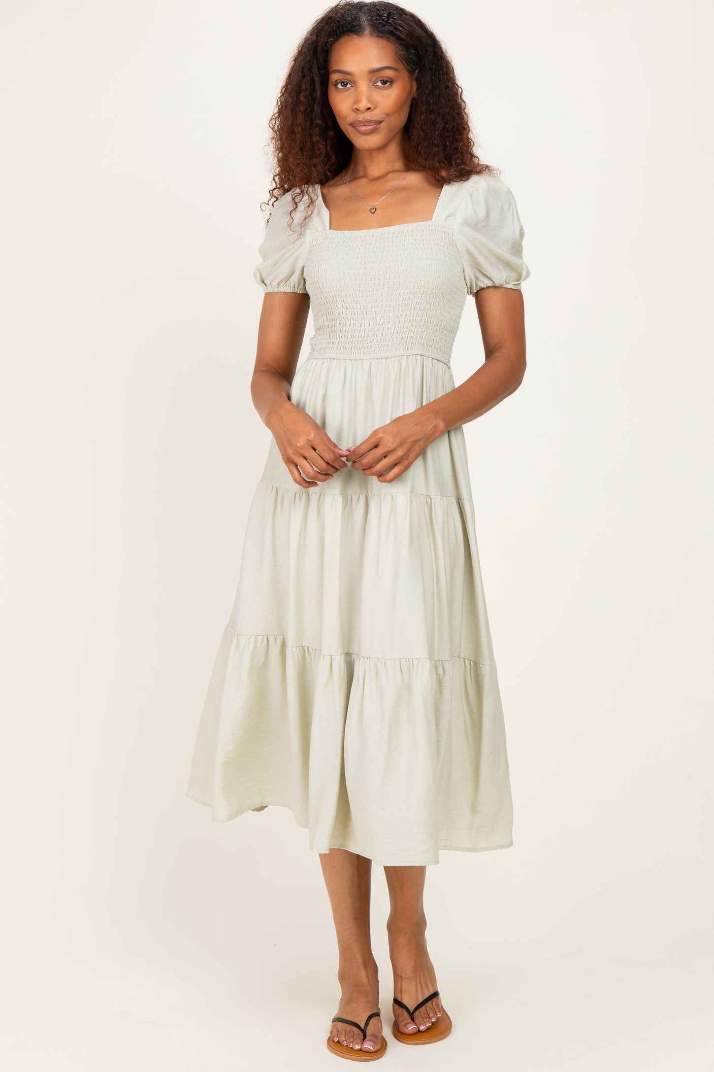 woman wearing a light green square neck smocked midi dress with puff sleeves and a tiered skirt