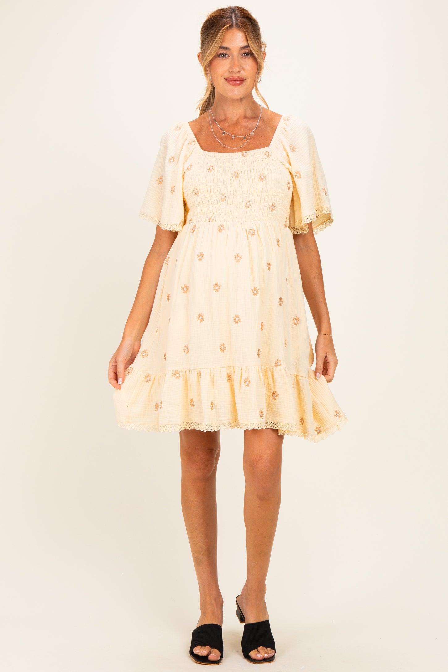 woman wearing a cream floral maternity dress with puff sleeves and ruffled hem