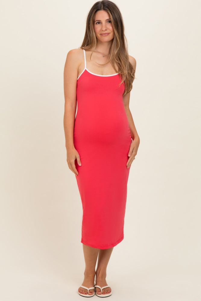 woman wearing a bright pink maternity dress with white straps and a visible baby bump