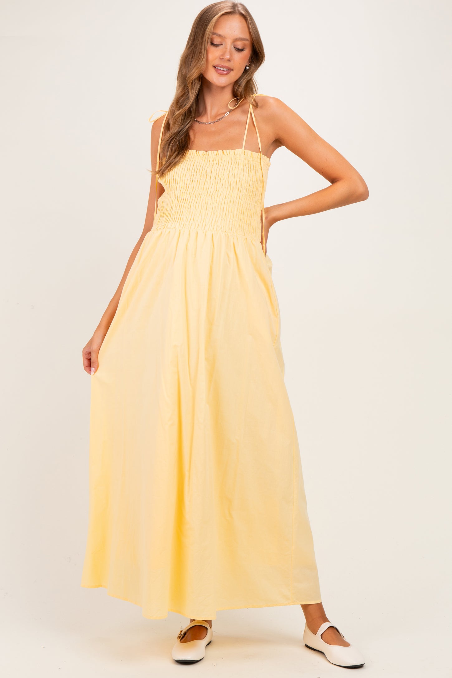 woman wearing a yellow smock style maternity maxi dress with adjustable straps and a relaxed fit