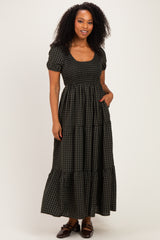 woman wearing a black and green gingham maxi dress with short puff sleeves and a tiered skirt, standing with hands in pockets