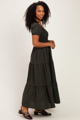 woman wearing a dark green and black checkered maxi dress with short sleeves and tiered skirt, standing sideways
