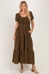 woman wearing a brown and black checkered tiered maxi dress with puff sleeves and pockets