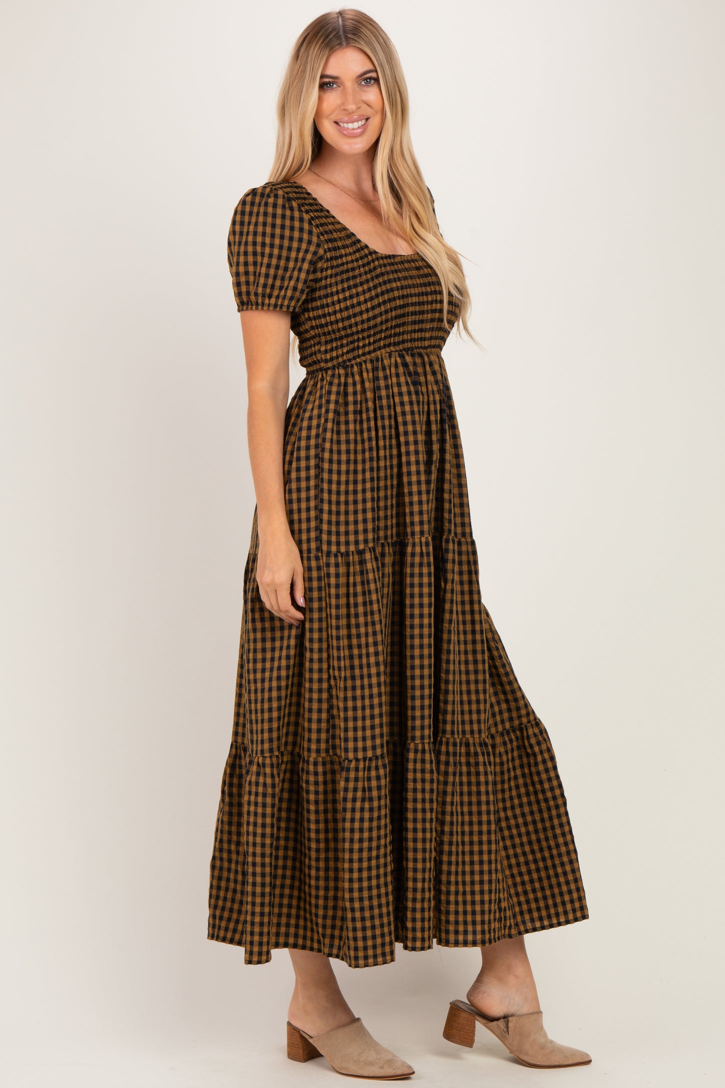 woman wearing a brown and black gingham print maxi dress with puff sleeves and tiered skirt