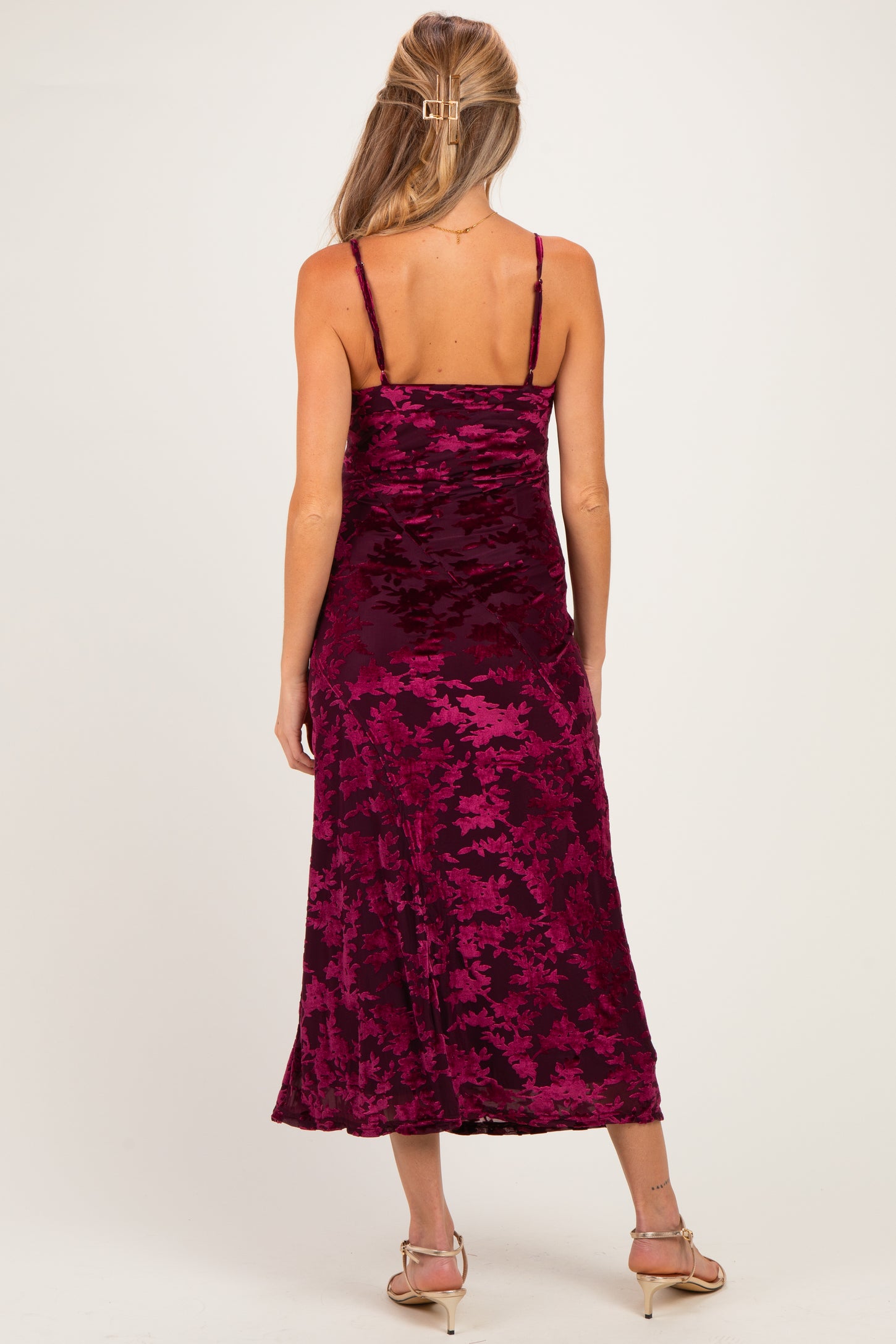 woman wearing a burgundy floral maternity dress with adjustable spaghetti straps and a flowing midi length