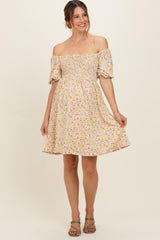 woman wearing a floral off-the-shoulder maternity dress with a smocked bodice and short puff sleeves