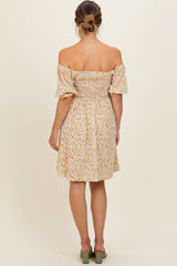 woman wearing a yellow floral off-the-shoulder maternity dress with a fitted bodice and puff sleeves, view from the back