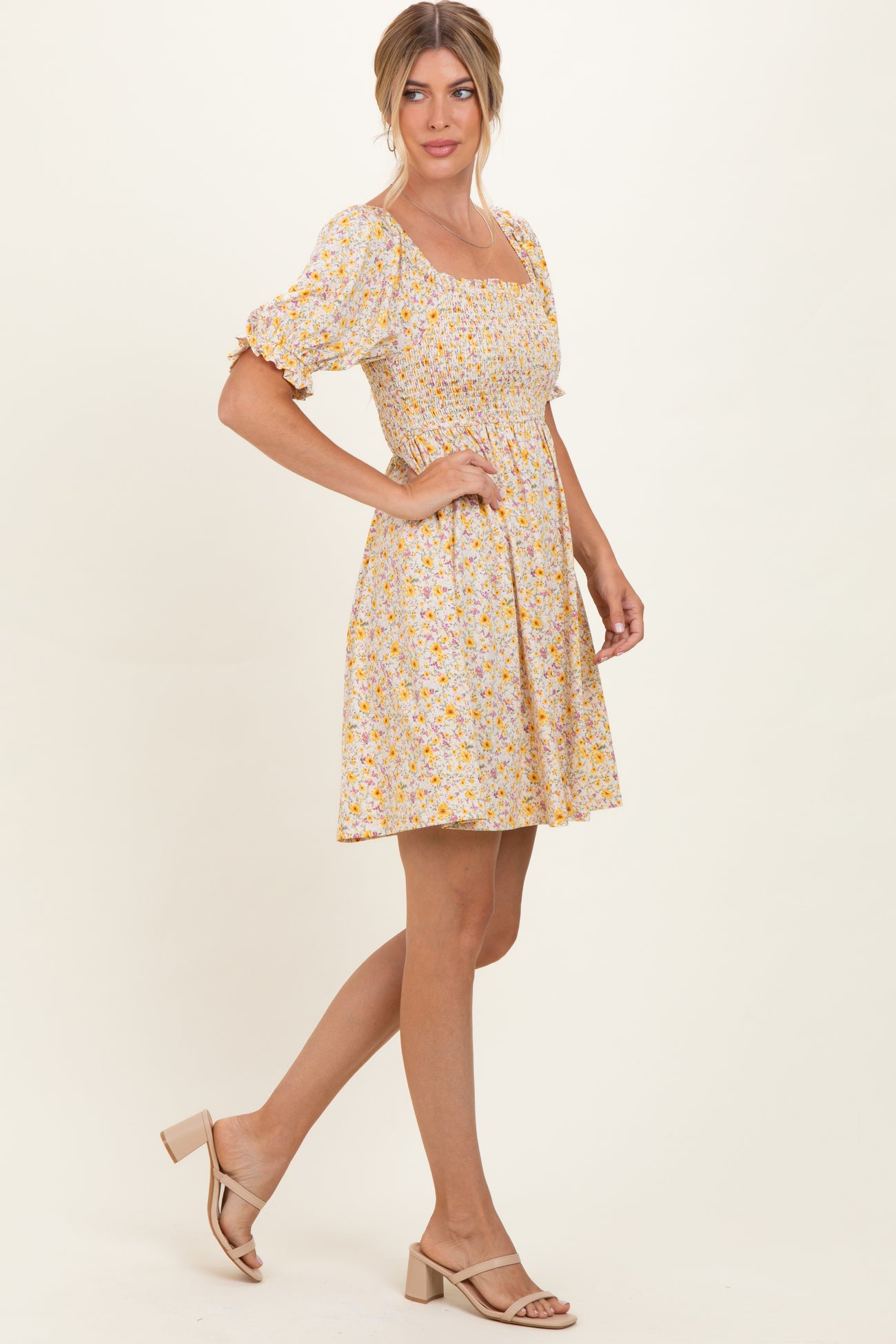 woman wearing a yellow floral short puff sleeve dress with a fitted bodice and flared skirt