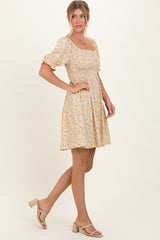 woman wearing a yellow floral short puff sleeve dress with a fitted bodice and flared skirt