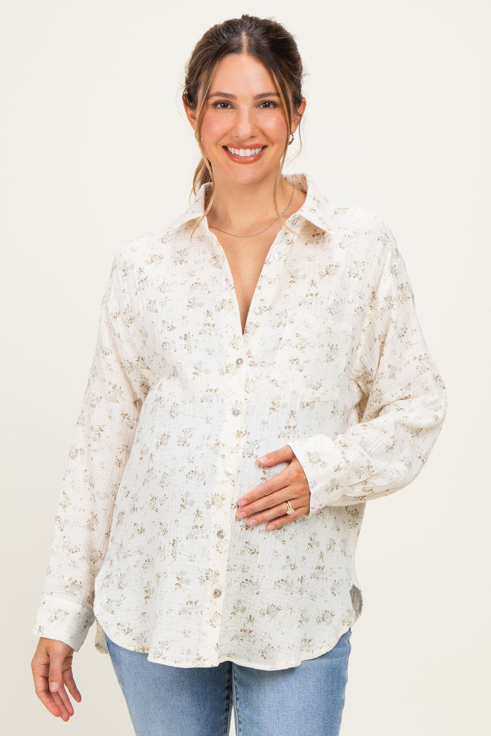woman wearing a cream floral button-up maternity shirt and holding her baby bump