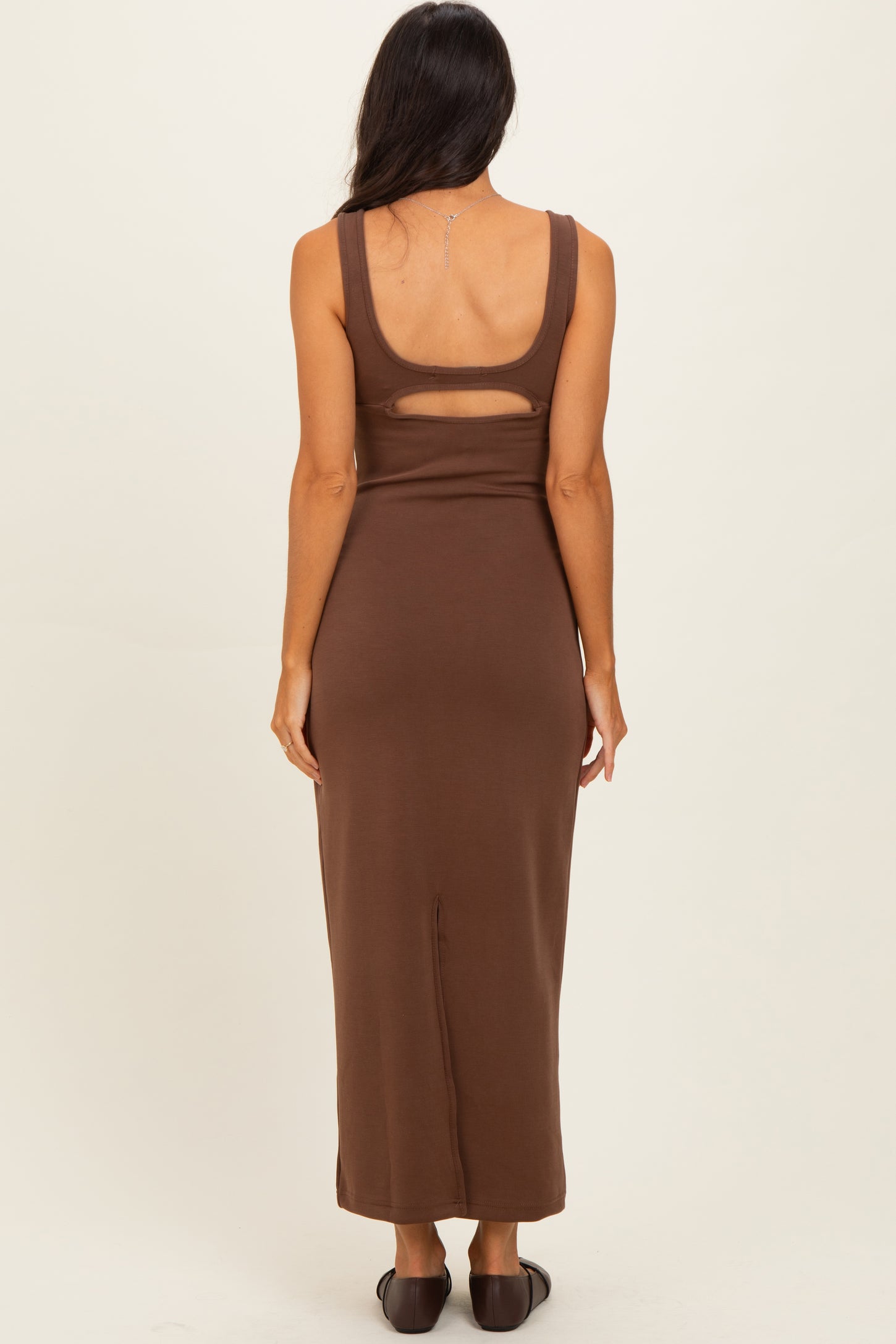 woman wearing a brown sleeveless maxi dress with a cut-out detail on the back
