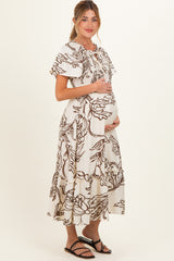 woman wearing a cream floral print maternity dress with flutter sleeves and a visible baby bump