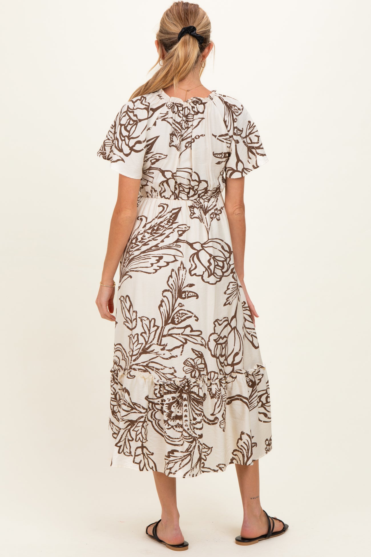 woman wearing a floral print maternity maxi dress with short flutter sleeves and a flowing skirt, seen from the back