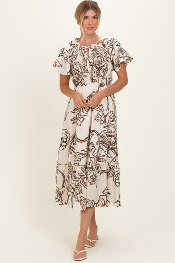 woman wearing a brown and cream floral print midi dress with puff sleeves and a tie neckline