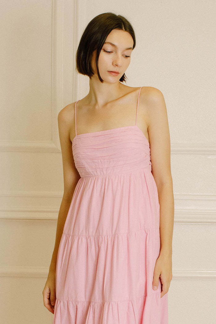 woman wearing a pink spaghetti strap tiered maxi dress with a ruched bodice