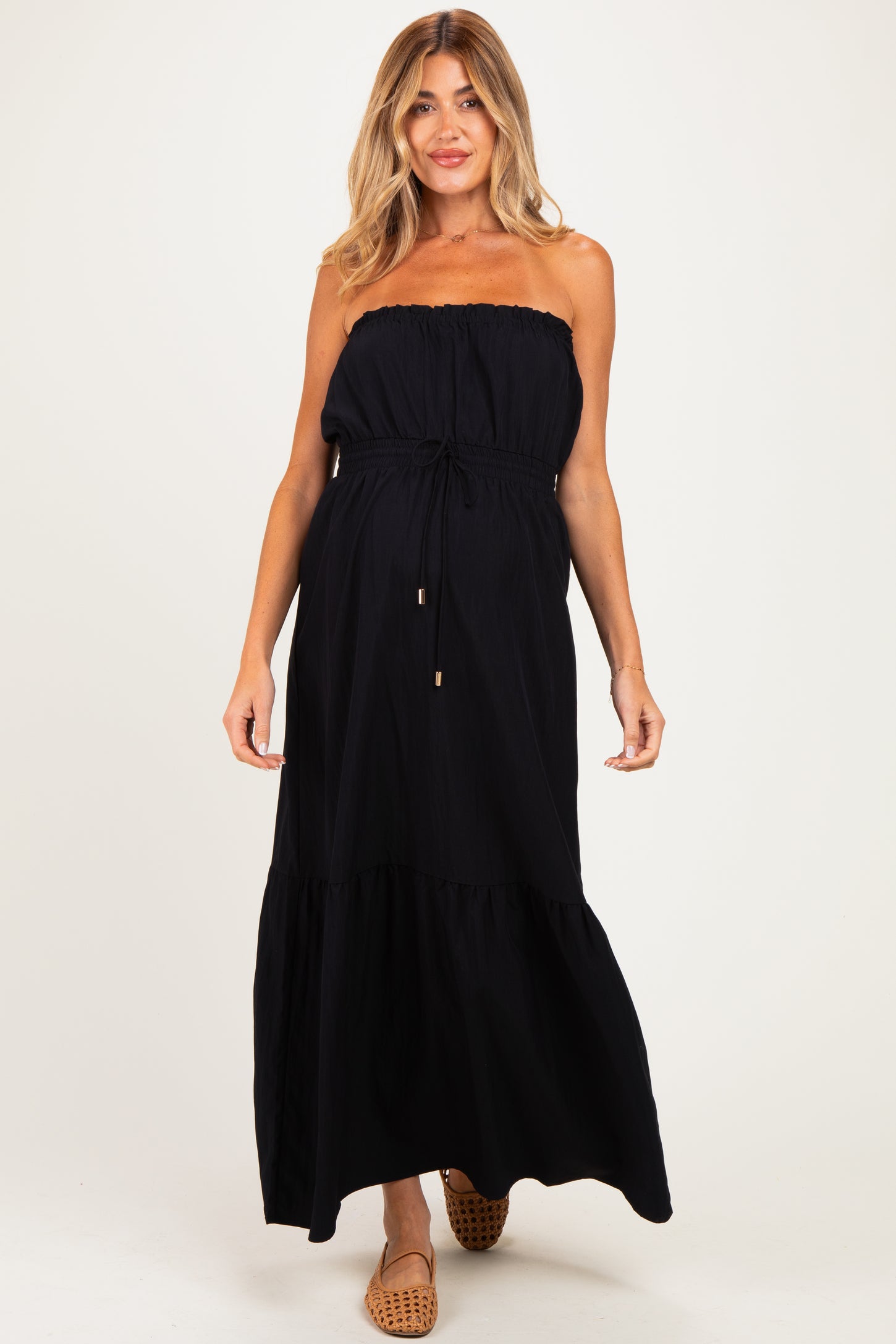 woman wearing a black strapless maternity maxi dress with an adjustable drawstring waist and tiered hemline