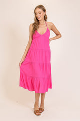 woman wearing a bright pink halter-style maxi dress with tiered ruffles and sandals