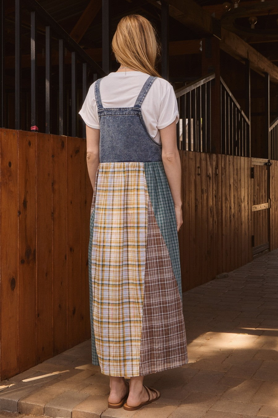 woman wearing a denim smock dress over a white t-shirt, featuring a patchwork design with plaid patterns