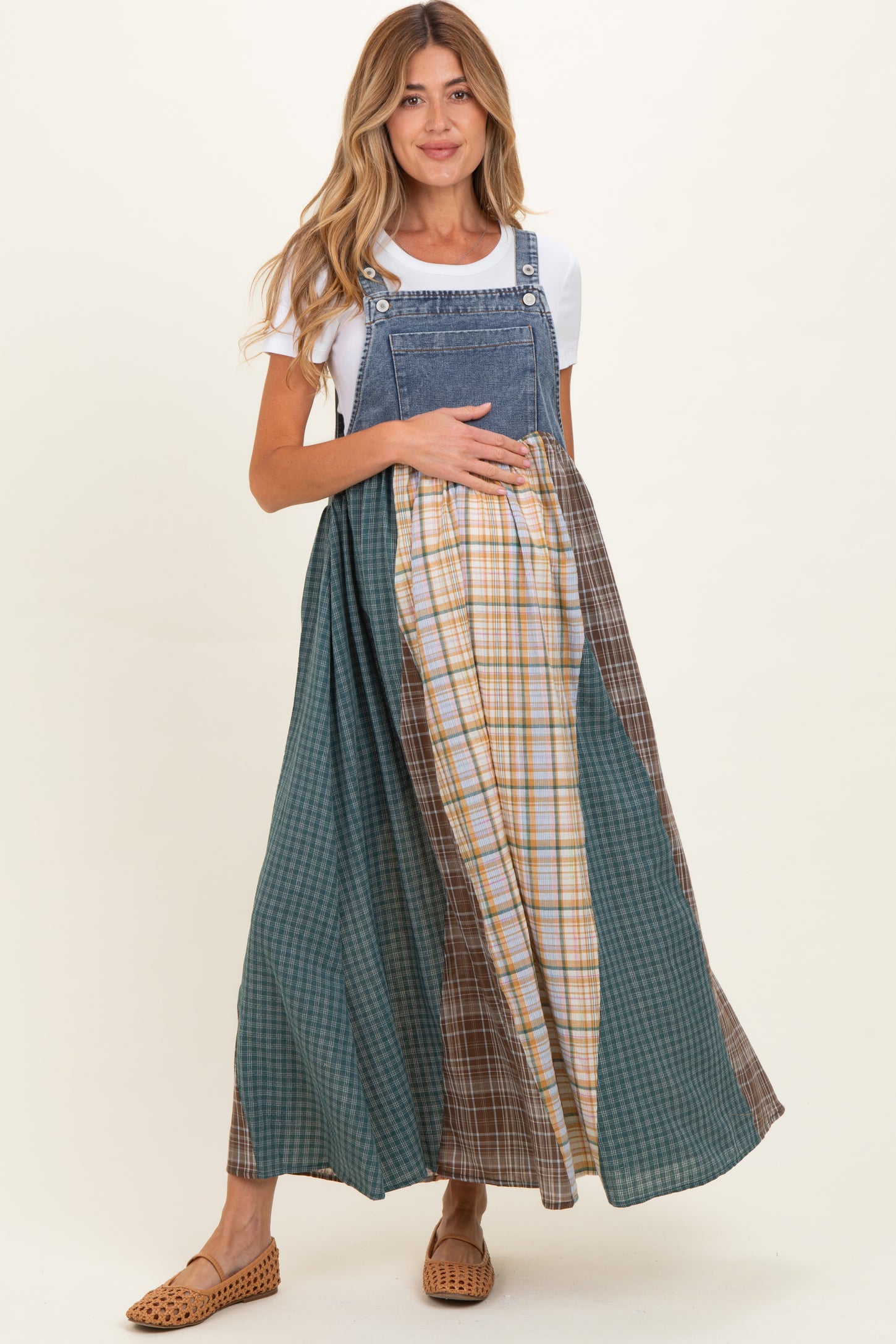 woman wearing a denim maternity maxi dress with mixed plaid patterns and holding her baby bump