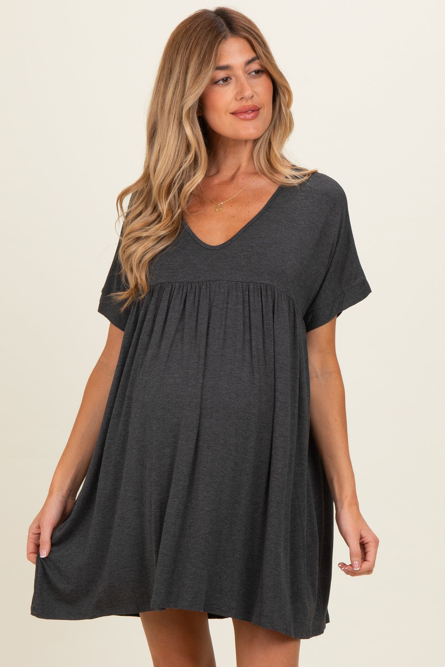 woman wearing a dark gray short-sleeve maternity dress with a flowy hem and a baby bump visible